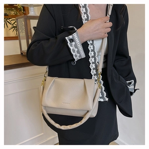 Detailed close-up of beige lychee grain leather fold handbag with a soft wide strap