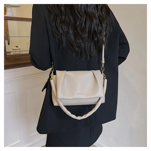 Detail of off-white lychee grain leather crossbody bag with pleated cloud handle and strap