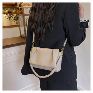 Detail of beige pleated cloud bag in lychee leather with golden hardware on model