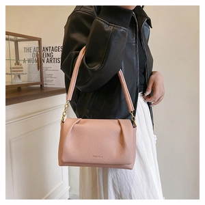 Close-up of litchi leather texture and ruched cloud detail on soft pink shoulder bag