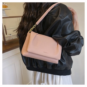 Detail view of pink lychee leather shoulder bag with gold chain strap on a model