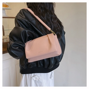 Close-up of pink lychee textured leather shoulder bag with stylish fold detail