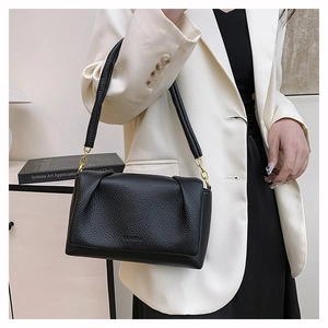 Detail of black pebbled leather handbag with elegant pleated design and gold hardware