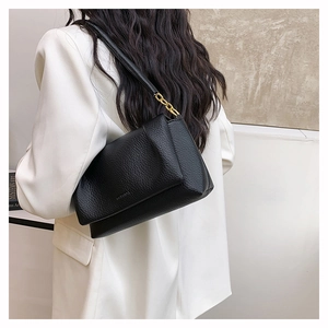 Close-up of black lychee grain leather shoulder bag with elegant gold chain strap details