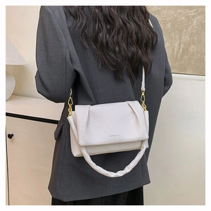 Detail of off-white lychee leather handbag with 3D pleats and gold-tone hardware on model