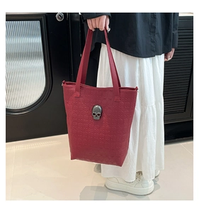 Detailed view of dark red tote bag featuring embossed skull pattern and 3D metal skull charm