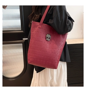 Detail of burgundy tote bag showing skull embossing and crystal skull metal ornament