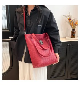 Detail of red tote bag with embossed skull pattern and metallic skull buckle closure