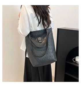 Detail of embossed skull pattern and rhinestone metal skull on large black tote bag