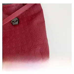 Detail of red leather tote featuring skull embossed pattern and crystal metal ornament