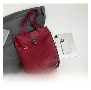 Deep red tote bag with embossed skull texture and metal hardware on a flat lay surface