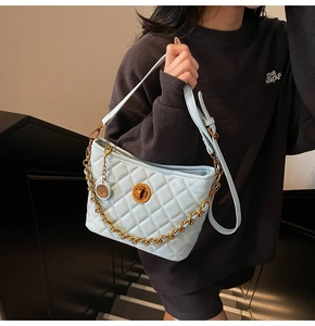 Macro shot of light blue quilted leather handbag with gold chain and metal twist lock