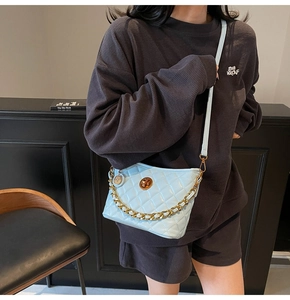 Detail of light blue quilted tote bag with gold chain strap and metal turn-lock closure