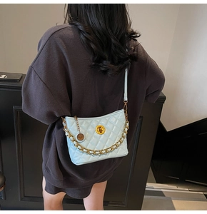 Detail of light blue quilted crossbody bag with gold chain and metal twist lock