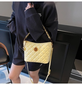 Detailed shot of yellow quilted chain bag with high-gloss finish and metallic turn-lock