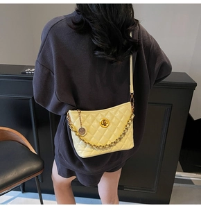 Detail of yellow quilted crossbody bag featuring gold chain and metallic twist lock