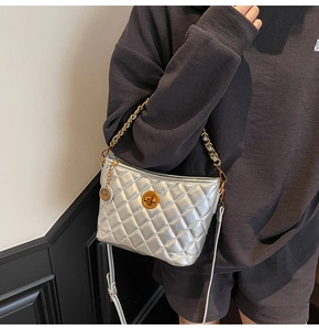 Detail of silver quilted shoulder bag featuring gold clasp and metallic chain strap
