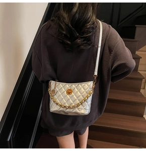 Detail of silver quilted crossbody bag with chunky gold chain strap and rotary metal lock