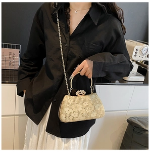 Pochette de soirée en dentelle et strass avec fermoir couronne portée par un mannequin
