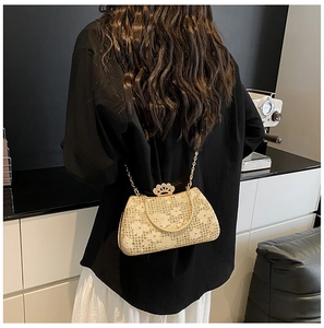 Détail de pochette de soirée en dentelle avec poignée dorée et fermoir couronne