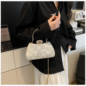 Détail du sac de soirée en dentelle blanche avec strass et fermoir couronne dorée