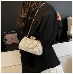 Détail d'un sac de soirée en dentelle blanche avec fermoir couronne dorée et chaîne