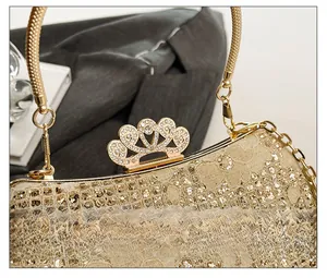 Détail de pochette de soirée avec dentelle fleurie dorée, paillettes et fermoir couronne