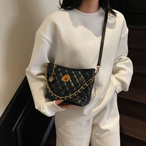 Black quilted crossbody bag with gold chain strap and metal lock closure for women