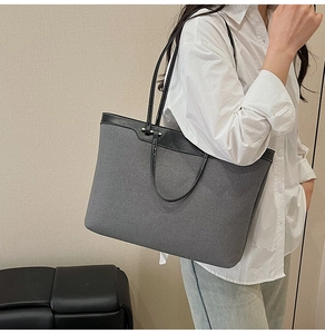 Detail of grey canvas tote with black leather trim showing texture and stitching