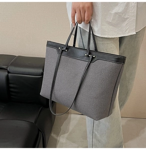 Close-up of contrast stitching on canvas tote bag with black leather handle details