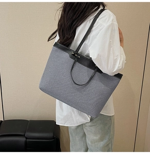 Detail view of large grey canvas tote bag with black leather trim and contrast stitching