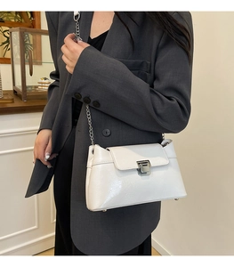 Détail d'un sac à bandoulière en cuir verni blanc avec chaîne et boucle en argent