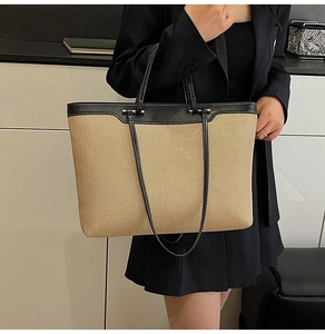 Detail of contrast stitching on the black leather handle of the large woven tote bag