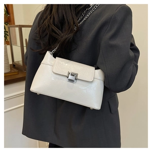 Détail du sac à bandoulière en cuir blanc brillant avec chaîne argentée et fermoir métal