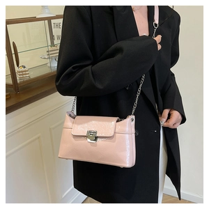 Détail d'un sac bandoulière en cuir verni rose avec une boucle métallique argentée