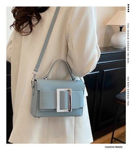 Detail of grey-blue pebble leather handbag with square silver buckle on a model