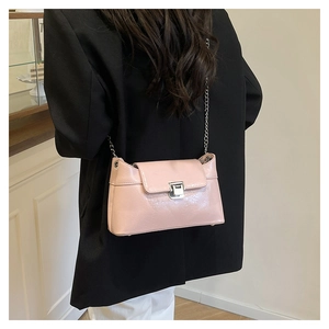 Sac bandoulière rose avec chaîne porté sur blazer noir, vue arrière de l'accessoire