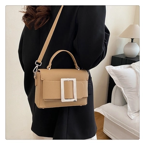 Close-up of pebble leather texture and silver rectangular metal buckle on khaki handbag