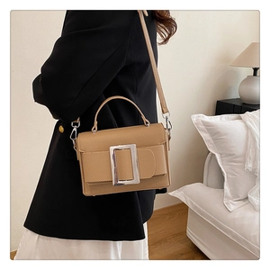 Close-up of khaki pebbled leather shoulder bag with large silver square buckle