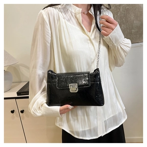 Détail du sac noir brillant à texture craquelée avec chaîne argentée et fermoir