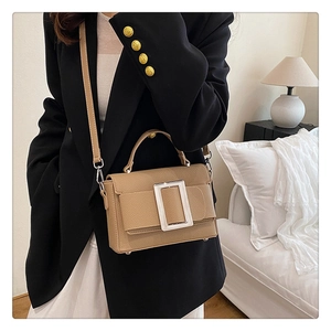 Khaki pebbled leather shoulder bag with large silver metal buckle on a model