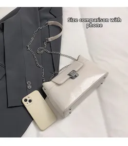 Petit sac bandoulière crème avec chaîne à côté d'un téléphone pour taille