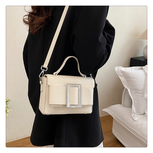 Close-up of lychee grain leather handbag featuring a large square silver buckle detail