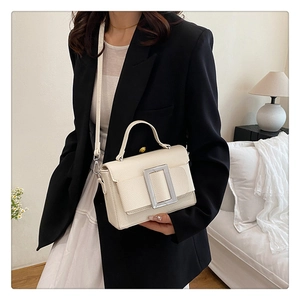 Close-up of cream textured leather handbag with a silver buckle in a cozy home setting