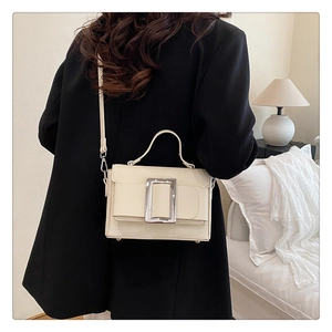 Close-up of beige lychee textured leather crossbody bag with silver square buckle
