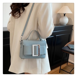 Detail of blue litchi pattern leather bag with large silver metal buckle and handle