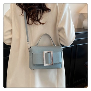 Detail of blue drawstring bag featuring silver rectangular buckle and pebbled texture