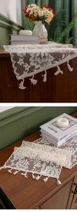 Detail of cream lace table runner featuring rose floral cutouts and tassel edge finish