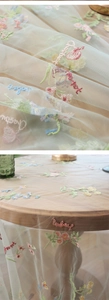 Detail of floral embroidery and text on beige mesh tablecloth over a round table