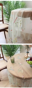 Close-up of floral mesh tablecloth with delicate embroidery and forget-me-not lettering